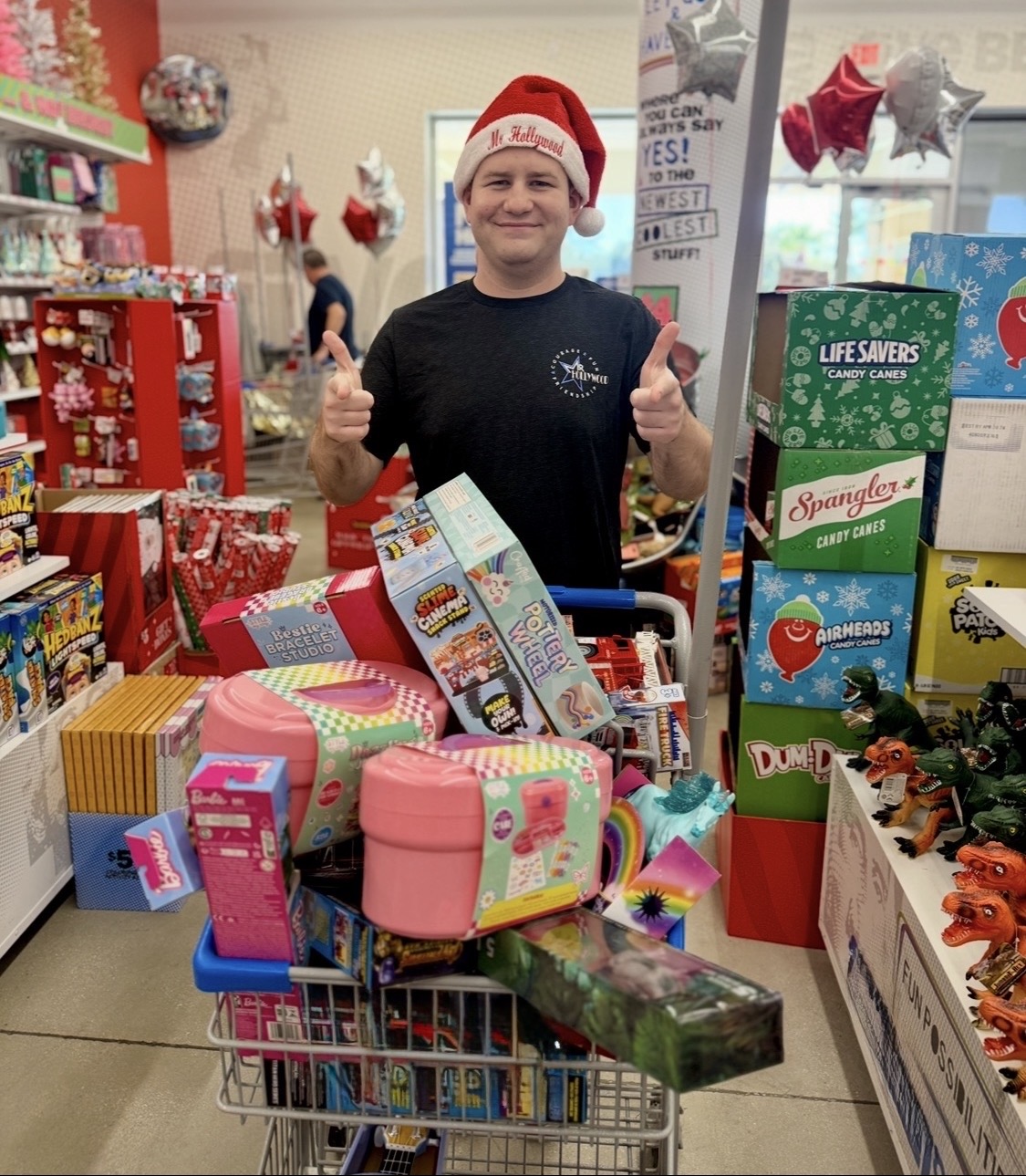 Stephen Lepore in a Mr. Hollywood Santa hat with a shopping cart full of toys for Christmas 4 Kids