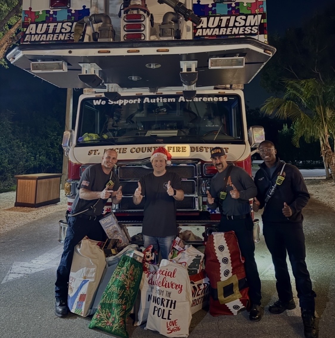 Stephen Lepore with firefighters in front of a fire truck and bags of donated Christmas gifts
