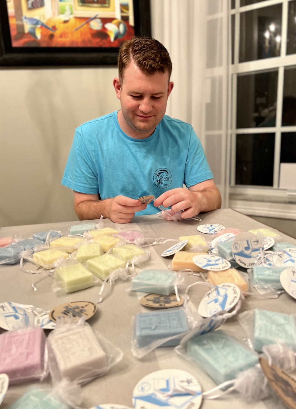 Stephen sitting at a table packaging and tagging his handmade soaps