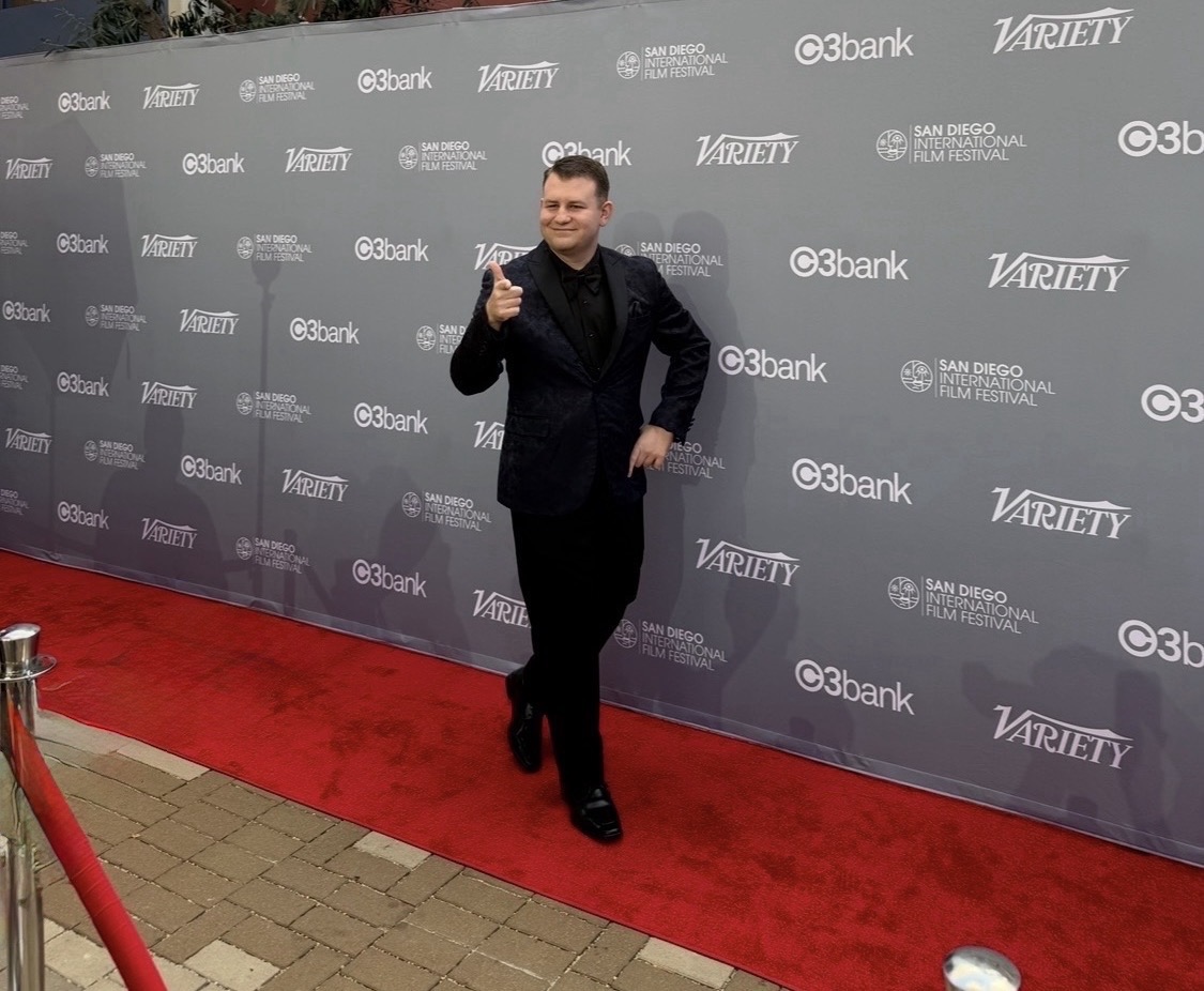 Stephen Lepore in a dark suit pointing toward the camera on the San Diego International Film Festival red carpet
